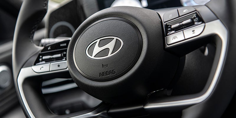 Vista interior de un coche moderno, donde se aprecian el salpicadero, el volante, las pantallas digitales y la palanca de cambios.