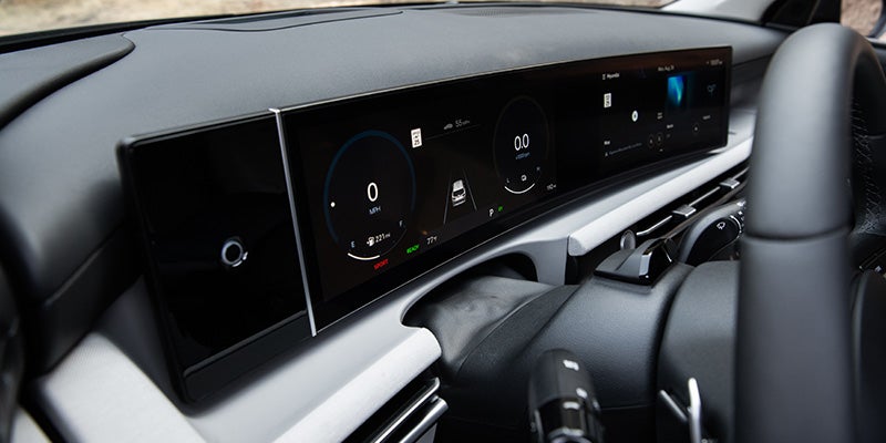 Vista interior del salpicadero de un coche moderno con volante, cuadro de instrumentos digital y pantalla de navegación.